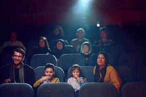 A modern family enjoys quality time together at the cinema, indulging in popcorn while watching a movie with their children photo