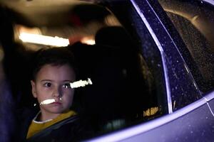 A young boy enjoys a car ride, captured through the window, as he observes the passing scenery. photo