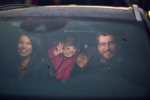 In the nighttime hours, a happy family enjoys playful moments together inside a car as they journey on a nocturnal road trip, illuminated by the glow of headlights and filled with laughter and joy photo