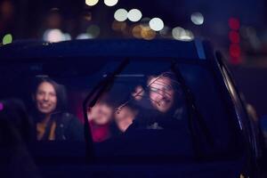In the nighttime hours, a happy family enjoys playful moments together inside a car as they journey on a nocturnal road trip, illuminated by the glow of headlights and filled with laughter and joy photo