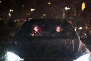In the midst of a nighttime journey, a happy family enjoys playful moments inside a car as they travel through rainy weather, illuminated by the glow of headlights, laughter, and bonding photo