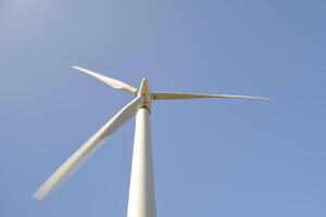 Close-up and low angle view of spinning blades of a wind turbine generating renewable energy photo