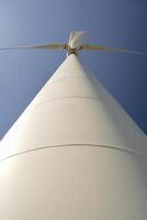 Close-up and low angle view of spinning blades of a wind turbine generating renewable energy photo