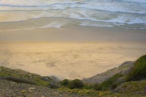 View on empty beach from a cliff. Location Bordeira on the Algarve coast in Portugal photo
