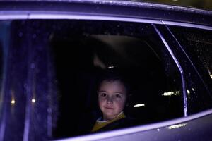 A young boy enjoys a car ride, captured through the window, as he observes the passing scenery. photo