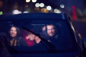 In the nighttime hours, a happy family enjoys playful moments together inside a car as they journey on a nocturnal road trip, illuminated by the glow of headlights and filled with laughter and joy photo