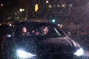 In the midst of a nighttime journey, a happy family enjoys playful moments inside a car as they travel through rainy weather, illuminated by the glow of headlights, laughter, and bonding photo
