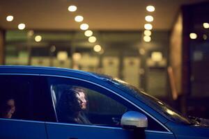 In the nighttime hours, a happy family enjoys playful moments together inside a car as they journey on a nocturnal road trip, illuminated by the glow of headlights and filled with laughter and joy photo
