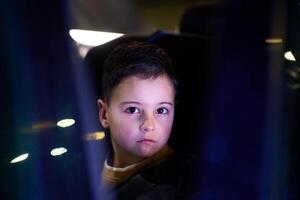 A young boy enjoys a car ride, captured through the window, as he observes the passing scenery. photo