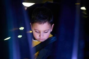 A young boy enjoys a car ride, captured through the window, as he observes the passing scenery. photo