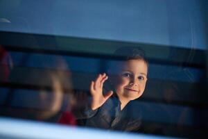 A young boy enjoys a car ride, captured through the window, as he observes the passing scenery. photo