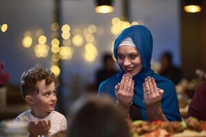 In a modern restaurant setting, a European Islamic family comes together for iftar during Ramadan, engaging in prayer before the meal, uniting tradition and contemporary practices in a celebration of photo