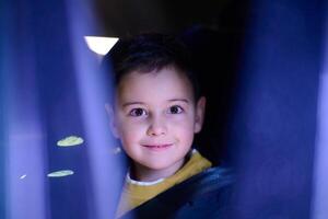 A young boy enjoys a car ride, captured through the window, as he observes the passing scenery. photo