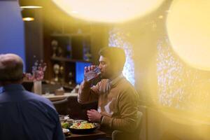 A son and his elderly father engage in heartfelt conversation while patiently awaiting their iftar meal, fostering intergenerational bonding and cherished moments of family connection photo