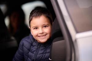 A young boy enjoys a car ride, captured through the window, as he observes the passing scenery. photo