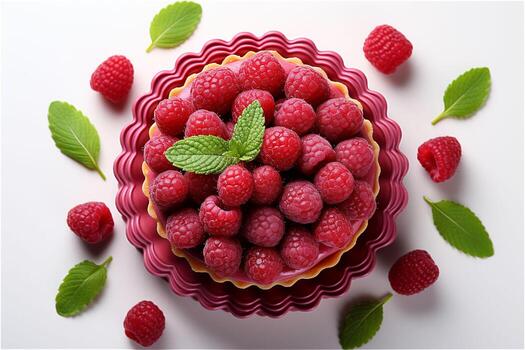 Top view of delicious raspberry tart with cream in a red plate with green leaves and berries around it on white background. High quality photo