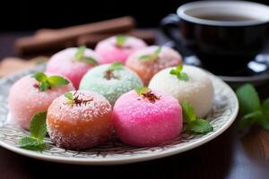 Pastel-colored mochi garnished with mint on a plate, accompanied by tea, presents a traditional Japanese dessert experience. photo