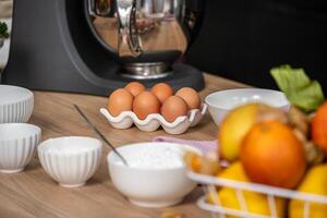 A well organized kitchen counter displays ingredients for baking, featuring a carton of eggs, bowls of flour and sugar, and fresh fruits, setting the scene for a home cooking adventure. photo