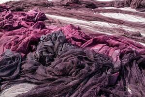 A detailed view of discarded maroon and white fishing nets piled on a dock, symbolizing environmental waste and the challenges of marine pollution and its impact on ecosystems. photo