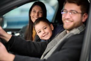 In the nighttime hours, a happy family enjoys playful moments together inside a car as they journey on a nocturnal road trip, illuminated by the glow of headlights and filled with laughter and joy photo