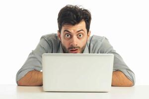 Young man looking shocked while using laptop photo