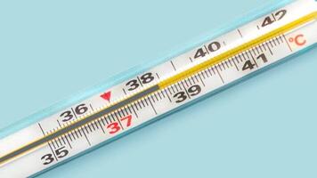 Mercury-in-glass thermometer with temperature mark 38,4 C on blue background flat lay close up stopmotion animation slow motion 4k video