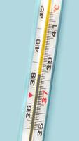 Mercury-in-glass thermometer with temperature mark 38,3 C on blue background flat lay close up vertical stopmotion animation slow motion 4k video