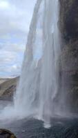 A vertical shot from behind a massive waterfall, enveloped in mist video