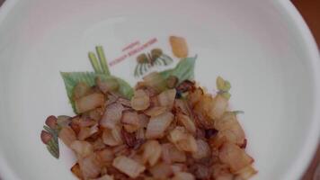 fried onions in a white plate on the table, top view video