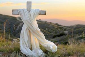 Wooden cross adorned with white cloth, glowing in sunset radiance photo