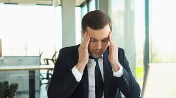 Stressed young man suffering from muscles tension, having painful head feelings due to computer overwork or sedentary working lifestyle. Tired employee overwhelmed with tasks in office video