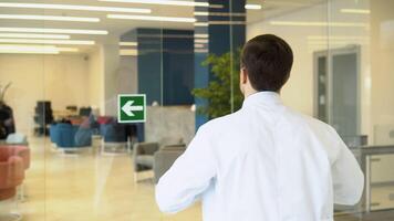 Doctor puts dressing gown on the go in clinic video