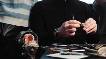 Dental technician working with orthodontic model and tools. Dental technician handling orthodontic model and tools in a classroom setting. video