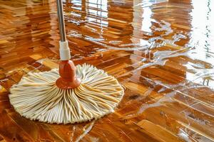 A close up of a mop on a wooden floor with water on it photo