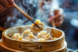A person holding chopsticks over a bowl of a dumplings photo