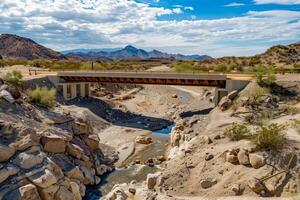 A bridge crossing a river in the desert photo
