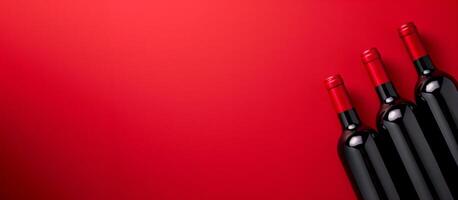 Three bottles of wine on a red background with copy space photo
