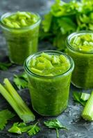 Three jars of green liquid with celery and celery stalks photo