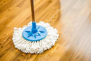 A close up of a mop on a wooden floor with a blue handle photo