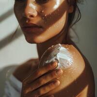 Close-Up Portrait of a Woman Applying Moisturizer on Sunlit Skin photo