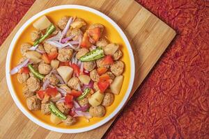 Ready to cook healthy food meal maker curry. Potatoes, onions, tomatoes, green chillies on yellow plate. photo