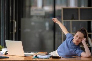 Businesswoman stretching lazy at the desk to relax while working in the office. Feeling stressed and achy from work. photo