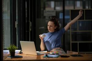 Businesswoman stretching lazy at the desk to relax while take a break from work and enjoy with coffee in the office. Feeling stressed and achy from work. photo