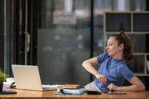 Businesswoman stretching lazy at the desk to relax while working in the office. Feeling stressed and achy from work. photo