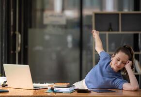 Businesswoman stretching lazy at the desk to relax while working in the office. Feeling stressed and achy from work. photo