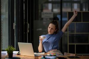 Businesswoman stretching lazy at the desk to relax while take a break from work and enjoy with coffee in the office. Feeling stressed and achy from work. photo