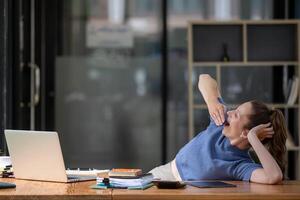 businesswoman yawning and stretching lazy while working with a laptop computer. Feeling bored and tired photo
