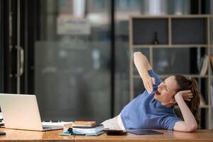 businesswoman yawning and stretching lazy while working with a laptop computer. Feeling bored and tired photo