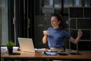 Businesswoman stretching lazy at the desk to relax while take a break from work and enjoy with coffee in the office. Feeling stressed and achy from work. photo