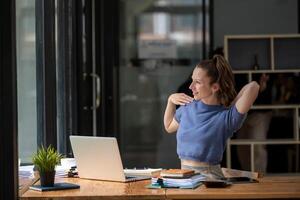 Businesswoman stretching lazy at the desk to relax while working in the office. Feeling stressed and achy from work. photo